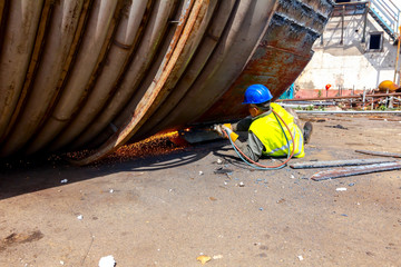 Worker is cutting old metal industrial equipment with acetylene torch