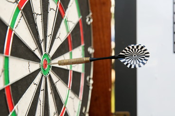 dart sticking out of a center of a darts board