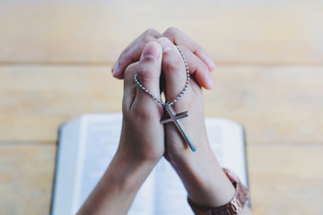 Cross on praying hand of Women faith jesus promise Pray for god  and holy bible on table