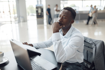 Black businessman at laptop in car dealership