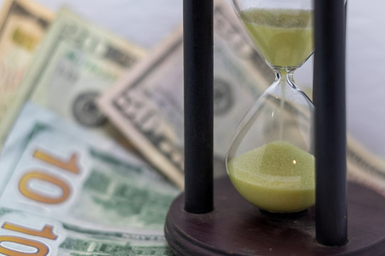 Time Is Money Concept. Philosophy Of Business Concept. Time Running. Hourglass And Money. Selective Focus. Text Space. Yellow Sand Timer