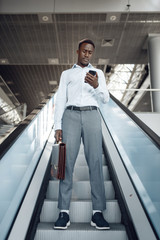 Businessman talking by phone on escalator in mall