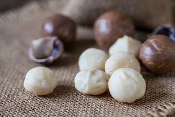 Macadamia nuts on sackcloth and wooden background