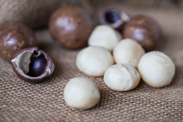 Macadamia nuts on sackcloth and wooden background