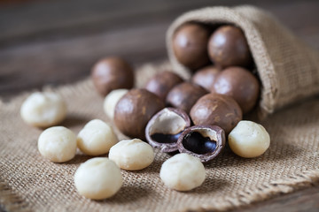 Macadamia nuts on sackcloth and wooden background