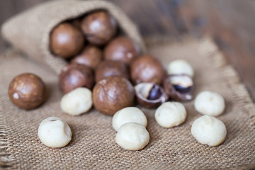 Macadamia nuts on sackcloth and wooden background