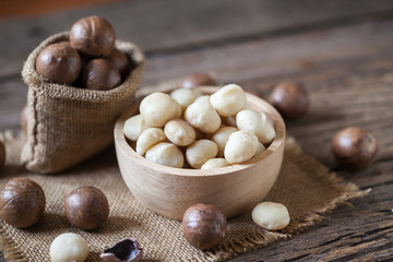 Macadamia nuts on sackcloth and wooden background