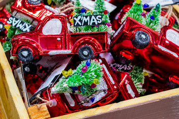 Close up a wooden box with a bunch of Christmas decorations in the form of a red car (truck) with a decorated Christmas tree in the back and the inscription " Merry Christmas"