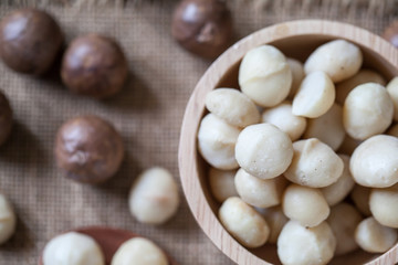 Macadamia nuts on sackcloth and wooden background