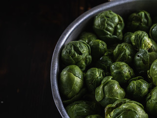 many small heads of Brussels sprouts in drops of water in a closeup lies in an aluminum drushlak pan with a handle.