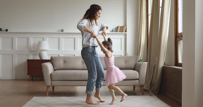 Active mom lifting spinning kid daughter dancing in living room