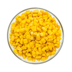 Top view of canned sweet corn in a glass bowl. Side dish and ingredient for salads. Isolated on a white background. Vegetarian.