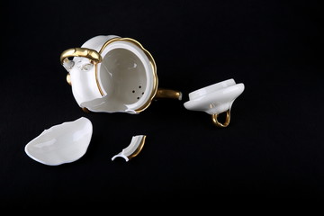 broken porcelain teapot on a black background