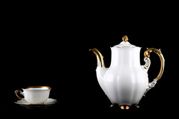 Vintage white coffee pot with gilding on a black background. porcelain teapot and cup on a dark background
