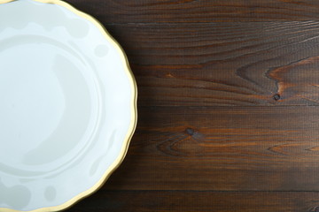 background of white plate with gilding on a wooden surface