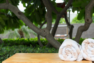Two towels on wooden table, soft focus garden on background. Spa, relax concept. Close-up, copy space