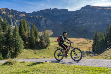 Obraz premium active senior woman riding her electric mountain bike in the autumnal atmosphere ofBregenz Forest mountains near Mellau, Vorarlberg,