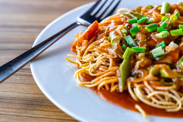 American Chopsuey served in a white plate on wooden surface