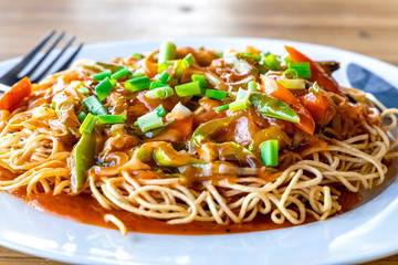 American Chopsuey served in a white plate on wooden surface