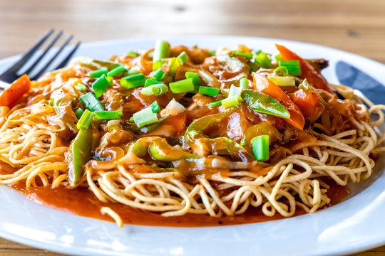 American Chopsuey served in a white plate on wooden surface