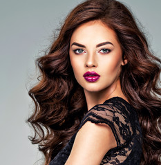Fototapeta premium Beautiful woman with long curly hair and bright purple make-up.