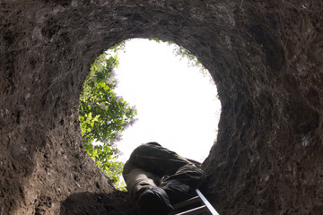A man climbs the ladder out of the deep hole - obrazy, fototapety, plakaty