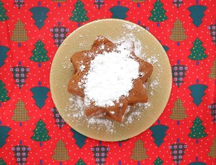 Pandoro, the traditional italian winter sweet bread, on a red tablecloth decorated with motifs in...