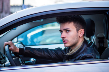 Handsome blue eyed young man sitting in his car, looking away