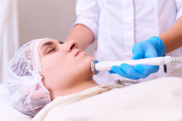 Young woman on RF face lifting procedure in a cosmetology clinic.
