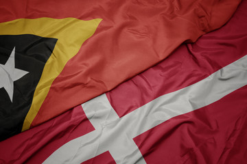 waving colorful flag of denmark and national flag of east timor.