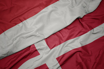 waving colorful flag of denmark and national flag of indonesia.