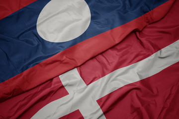waving colorful flag of denmark and national flag of laos.