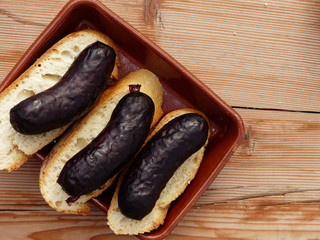 Morcilla/Baldana on a ceramic plate with bread on a wooden table. (Top view)