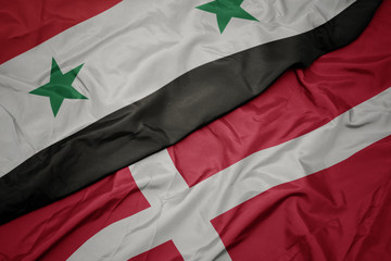 waving colorful flag of denmark and national flag of syria.
