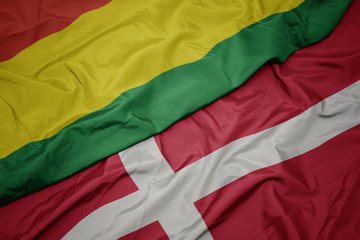 waving colorful flag of denmark and national flag of bolivia.
