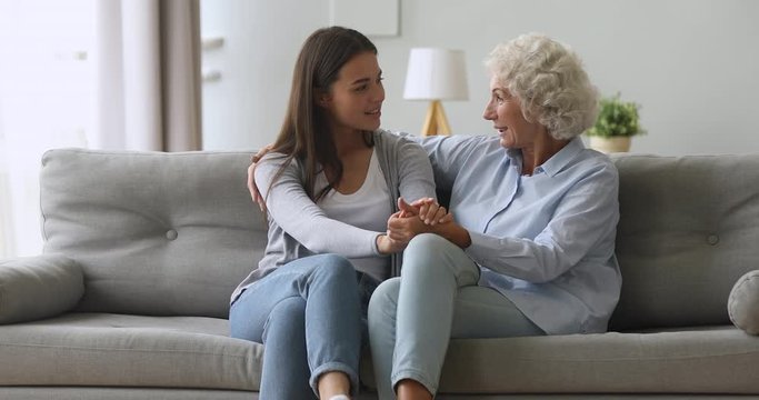 Happy young daughter and senior mother talking bonding at home