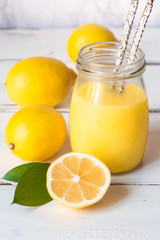 lemon curd in a jar and lemons on white background