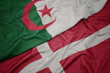 waving colorful flag of denmark and national flag of algeria.