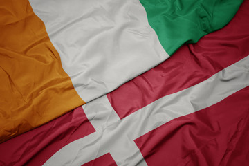 waving colorful flag of denmark and national flag of cote divoire.