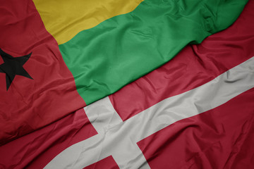 waving colorful flag of denmark and national flag of guinea bissau.