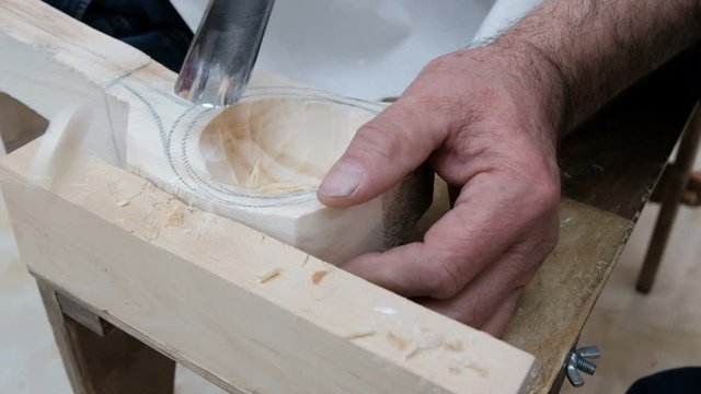 Footage of male woodworker who carves spoon. Woodcarver work in his workshop. Handicraft men's work or a hobby for carving wood products. Folk applied art.