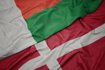 waving colorful flag of denmark and national flag of madagascar.