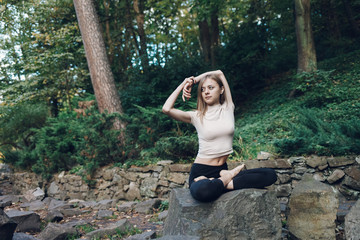  Girl sitting in yoga pose. Sports woman is warming up outdoors