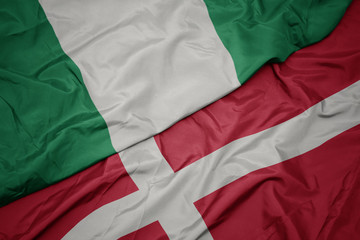 waving colorful flag of denmark and national flag of nigeria.