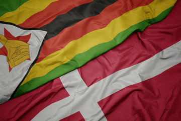 waving colorful flag of denmark and national flag of zimbabwe.