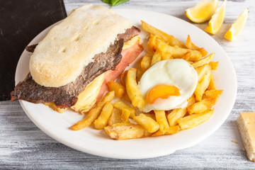 sandwich de carne con papas fritas y huevos fritos