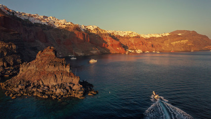 Aerial drone photo of world famous beautiful sunset at traditional and picturesque village of Oia with golden colours, Santorini island, Cyclades, Greece