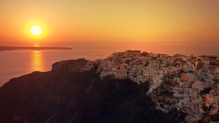 Aerial drone photo of world famous beautiful sunset at traditional and picturesque village of Oia with golden colours, Santorini island, Cyclades, Greece