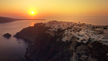 Aerial drone photo of world famous beautiful sunset at traditional and picturesque village of Oia with golden colours, Santorini island, Cyclades, Greece