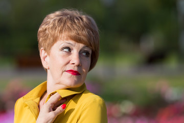 Adult short-haired best woman portrait. Woman senior citizen in sunny weather outdoors.